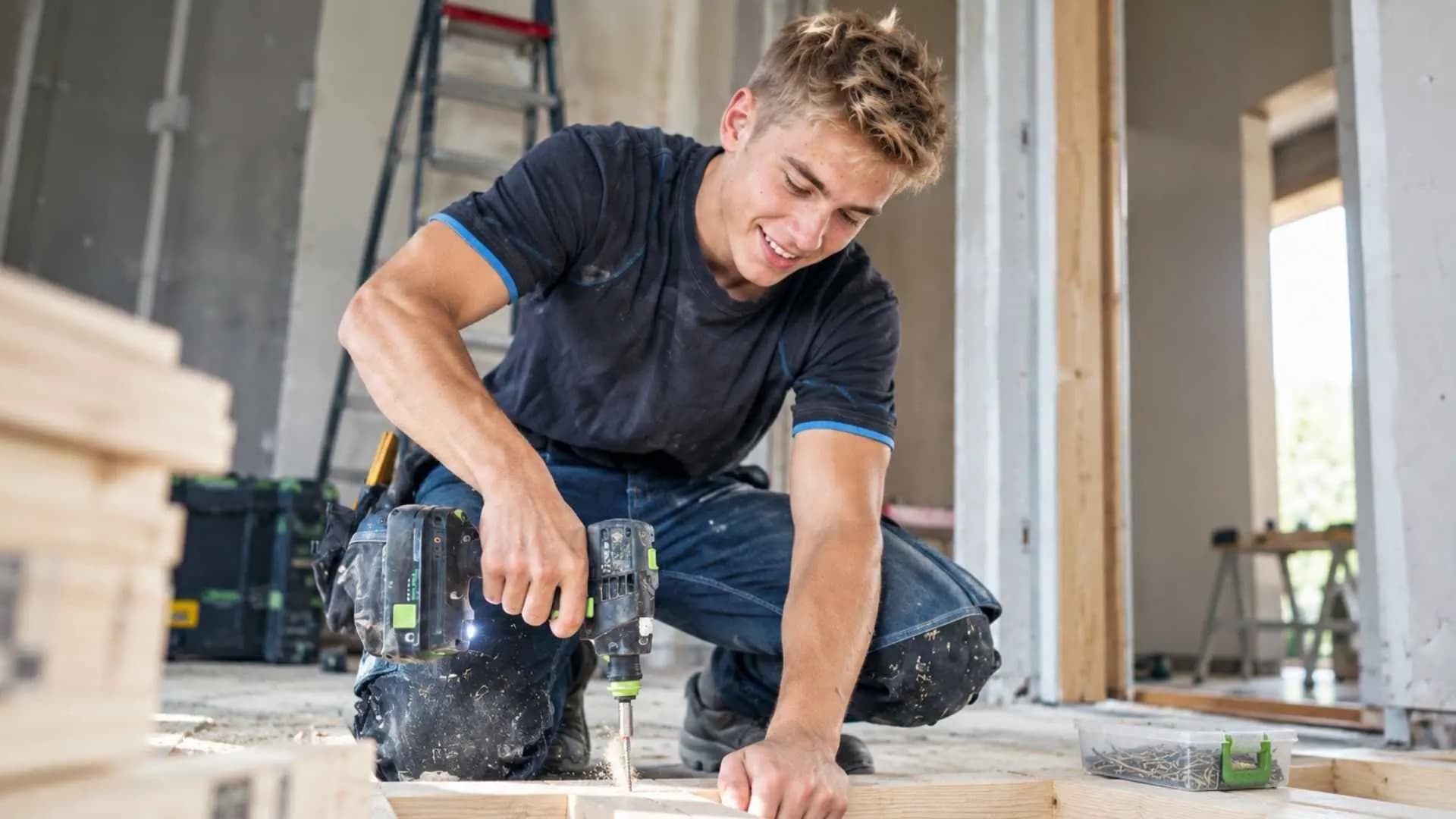 A carpenter screwing timber battens in place on site.